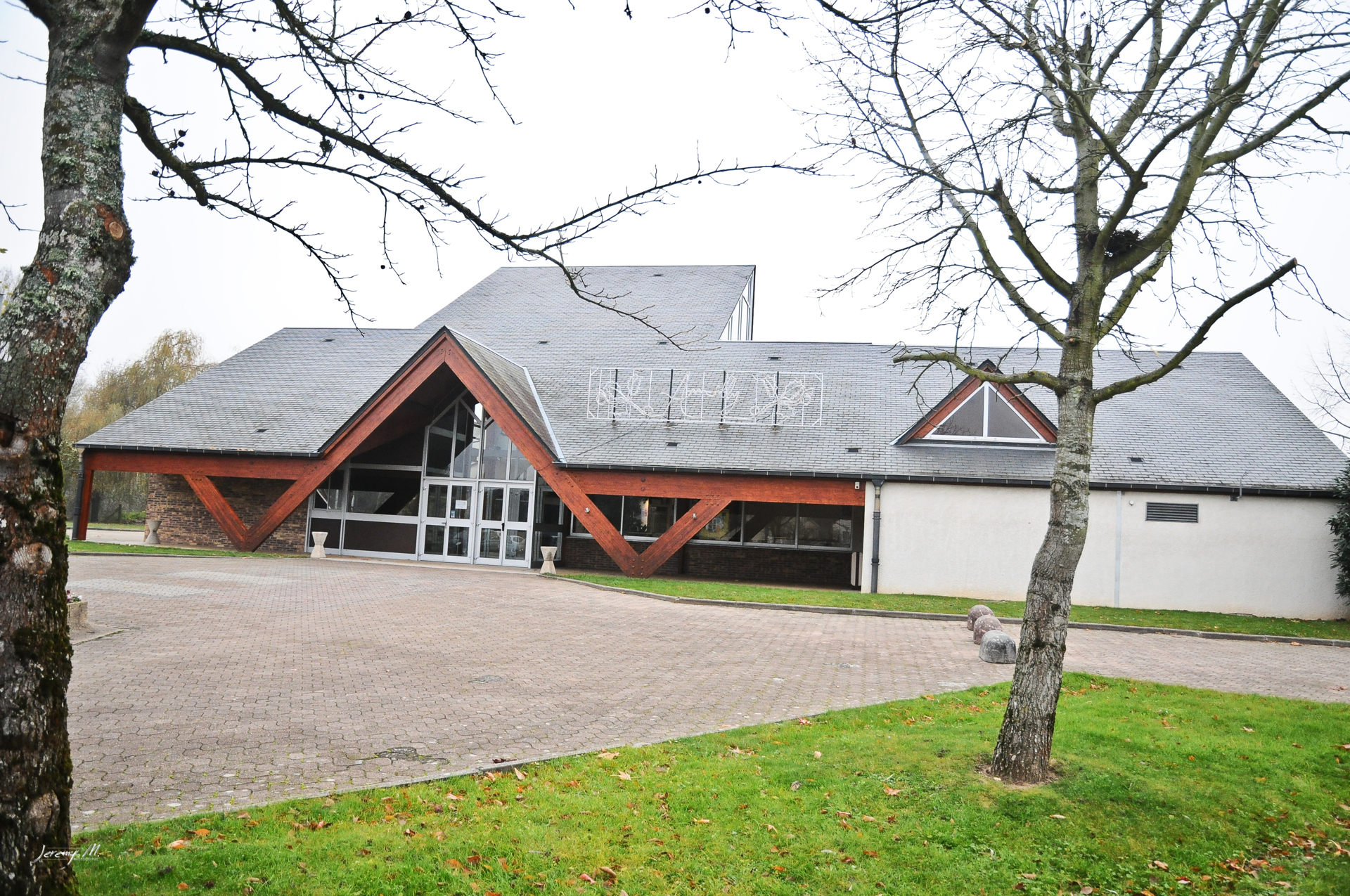 Salle de spectacle Jean Vilar, grand bâtiment avec poutres apparentes rouges.